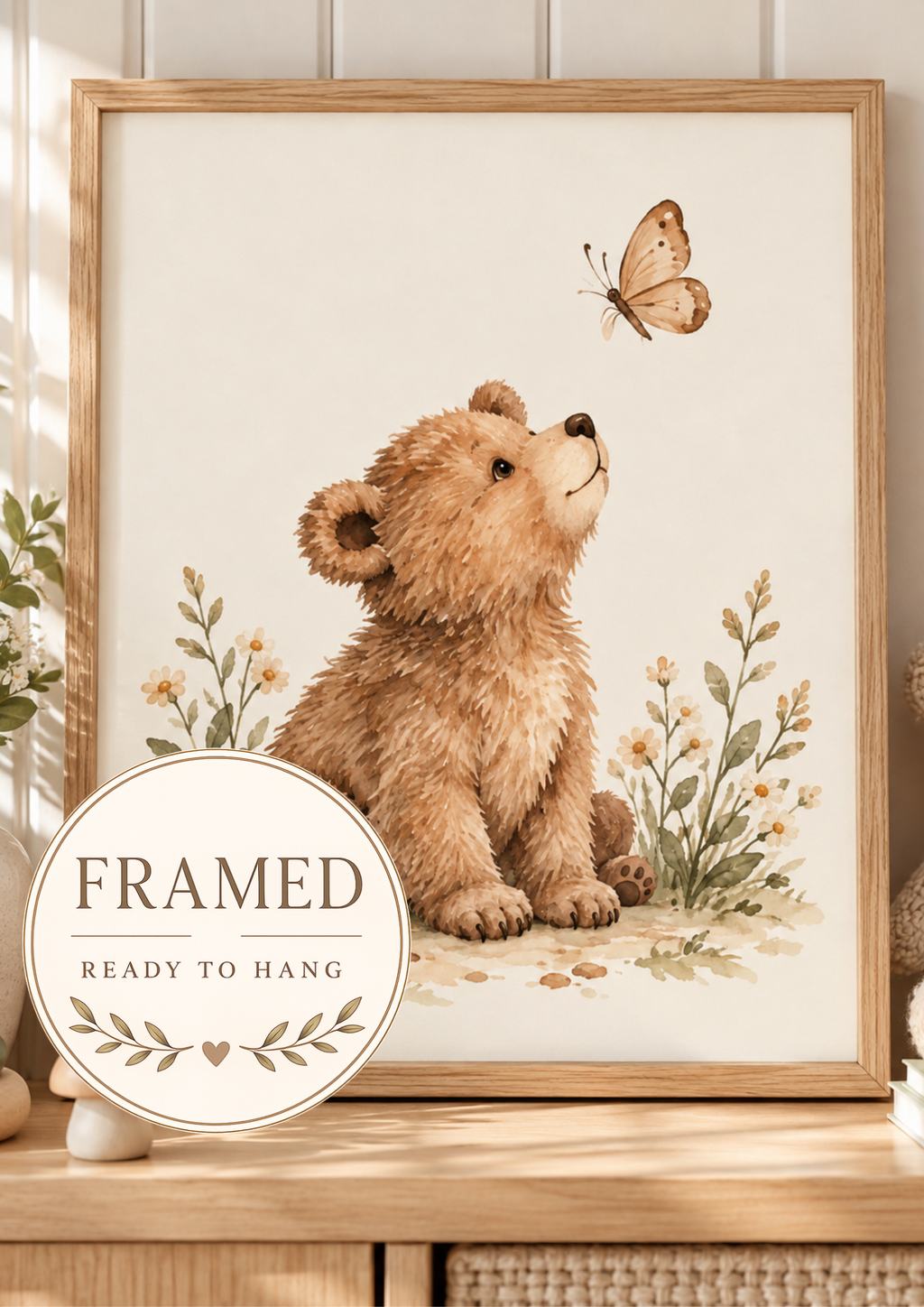 Watercolour teddy bear with paws resting down, looking up at a butterfly among daisies and soft foliage; framed and ready to hang badge