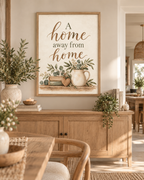 A Home Away From Home quote in warm brown lettering with sage-green botanical foliage, vintage books, wooden heart and rustic ceramic jug styled in a dining area