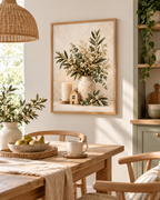 Neutral botanical artwork with white flowers, foliage, a cream vase, candle and wooden house beside a dining table