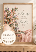 A calmer mind creates a kinder life quote with pink and ivory flowers, sage foliage, ceramic vase, candle, books and blush knitted throw; framed and ready to hang badge
