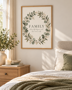 Family where life begins and love never ends quote surrounded by a sage green eucalyptus and white flower wreath styled in a bedroom
