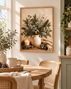 Winter botanical still life with evergreen foliage, eucalyptus, white berries and pine cones in a rustic jug, candle, brass bells and knitted blanket styled in a dining area