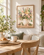 Pink wildflowers and white daisies with lavender stems and green foliage in a cream ceramic jug on a rustic tabletop styled in a breakfast nook