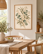 Delicate sage green eucalyptus, olive-toned foliage and ivory-white flowers on a warm neutral background styled in a dining area