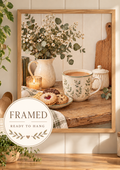 Cosy coffee and biscuits still life with botanical ceramic mug, white flowers, sage greenery, candle and rustic wooden tabletop; framed and ready to hang badge