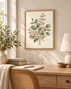 Sage green leaves and delicate blush pink flowers in a botanical watercolour arrangement styled in a desk
