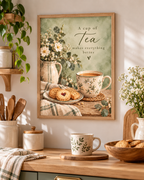 A cup of tea makes everything better quote with floral teacup, biscuits, daisies, ceramic jug and sage green background styled in a kitchen