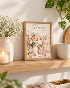 Forever Starts Here wedding artwork with blush and ivory roses, muted green foliage, champagne glasses, engagement ring, ribbons and wedding stationery styled in a shelf display