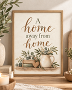 A Home Away From Home quote in warm brown lettering with sage-green botanical foliage, vintage books, wooden heart and rustic ceramic jug; print only, frame not included