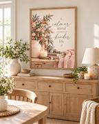 A calmer mind creates a kinder life quote with pink and ivory flowers, sage foliage, ceramic vase, candle, books and blush knitted throw styled in a dining room