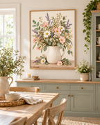 Pink wildflowers and white daisies with lavender stems and green foliage in a cream ceramic jug on a rustic tabletop styled in a dining room