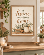 A Home Away From Home quote in warm brown lettering with sage-green botanical foliage, vintage books, wooden heart and rustic ceramic jug styled in a kitchen counter