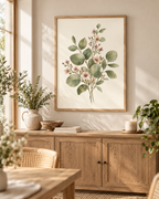 Sage green leaves and delicate blush pink flowers in a botanical watercolour arrangement styled in a dining area