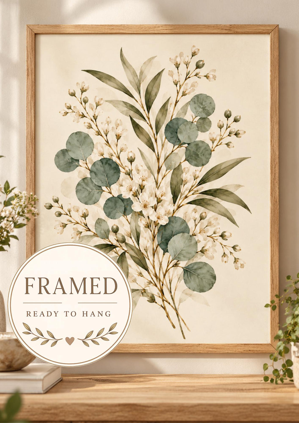 Delicate sage green eucalyptus, olive-toned foliage and ivory-white flowers on a warm neutral background; framed and ready to hang badge